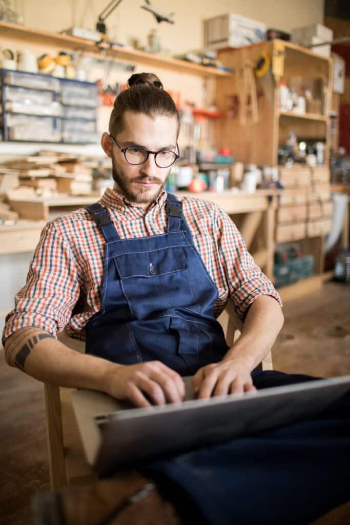 Meșter în atelier lucrând pe laptop