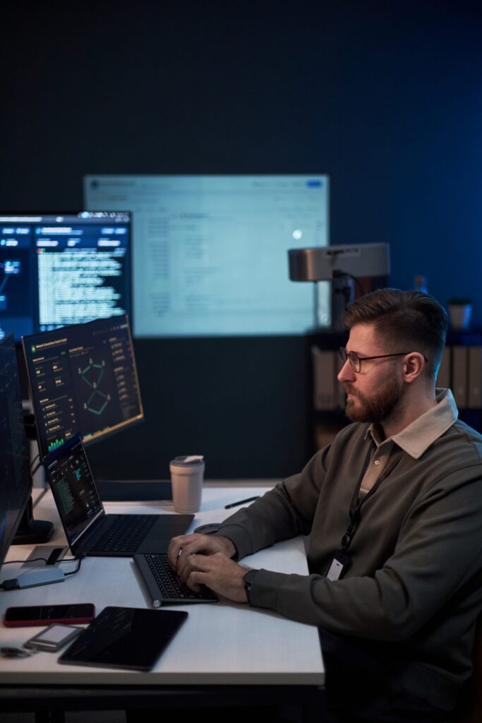Programator lucrând la cod pe mai multe monitoare